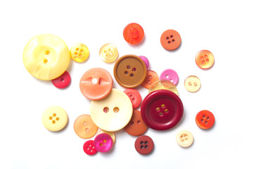 closeup of red and orange buttons and red cotton yarn on white background