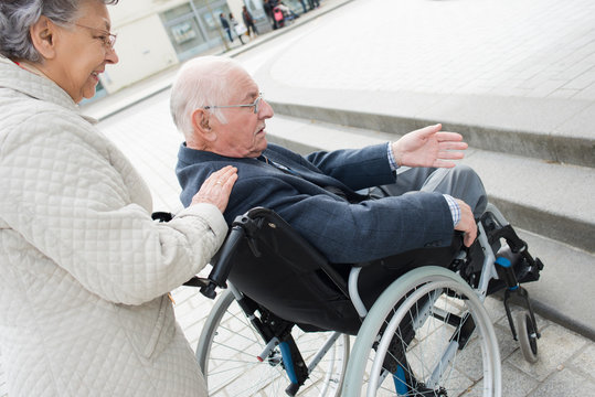 wife helping his husband on wheelchair