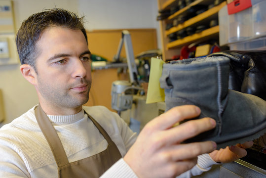 experienced young cobbler looking at a boot
