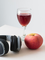wine apple in glass with black hreadphone on white background,
