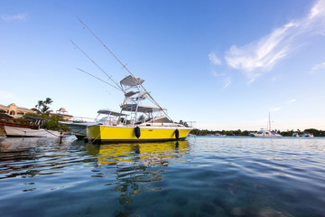 Fototapeta na wymiar Yellow fishing boat in the port with clear water and blue sky