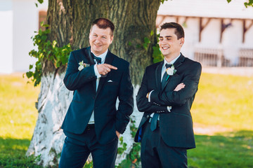 Groom posing with groomsmen on a sunny wedding day. Groom show finge to groomsmen "You next"