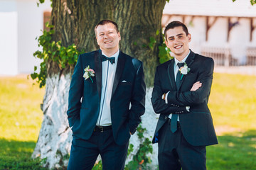 Groom posing with groomsmen on a sunny wedding day. Groom show finge to groomsmen 