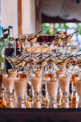 Delicious wedding reception candy bar dessert table. A lot of alcohol and glasses. Coktails and sweets. Wedding party table.