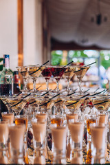 Delicious wedding reception candy bar dessert table. A lot of alcohol and glasses. Coktails and sweets. Wedding party table.