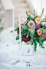 Table set for wedding or another catered event dinner. Catering in restaurant for wedding party. Served tables with pink and red flowers. 