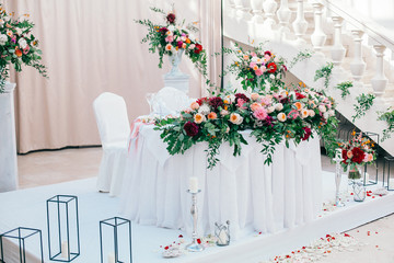 Table set for wedding or another catered event dinner. Catering in restaurant for wedding party. Served tables with pink and red flowers. 