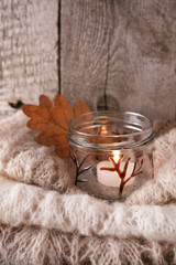 Obraz na płótnie Canvas Details of still life in the home interior living room. Beautiful candlestick, warm cloth, candle on wooden background. Vintage, rustic. Cozy autumn fall winter concept