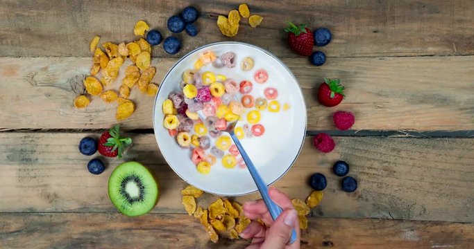 Stop motion of hand with a spoon taking cereal on a bowl over wooden table. Shot in 4k resolution