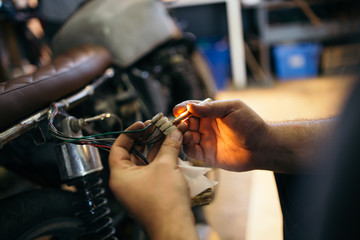 Close up shot of experienced man working in custom made motorcycle workshop.