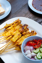 Grilled pork satay with peanut sauce, vagetables vinegar and toast, Thai food style name Hmu satay on wooden table