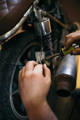Close up shot of experienced man working in custom made motorcycle workshop.