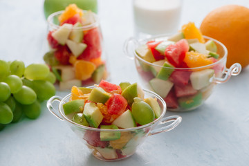 Pieces of tropical fruits in a glass. Sliced orange, apple, slices of watermelon in glass bowl. Citrus fruits