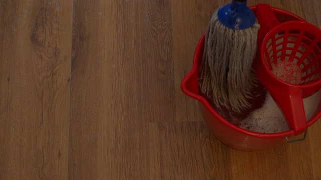 mop is rinsing in bucket and cleans a wooden floor
