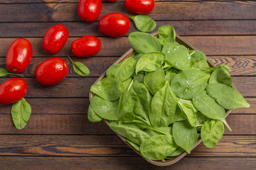 Tomatoes and spinach leaves on wooden table