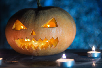 Cool pumpkin killer on Halloween in smoke on dark background with candles