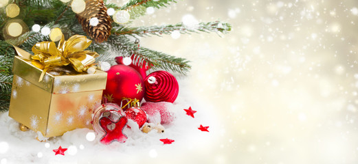 fir tree and red christmas decorations and gift box on white snow , winter banner