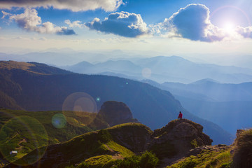 person in the beautiful mountain landscape of Ceahlau, Romania. Lens flare added in the photo