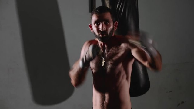 Male bearded boxer exercising shadow boxing.
