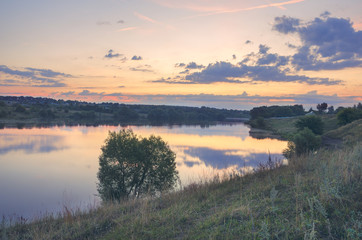 Tranquil summer landscape with river and beautiful clouds in twilight time.