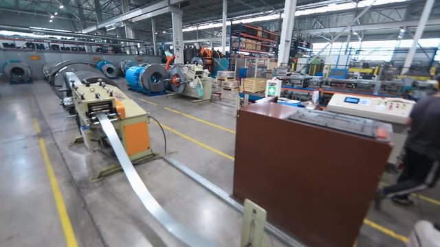 metal coil rotate on the machine. strip of steel goes to the metal rolling machine. create profiles. rolls of galvanized steel. rolls of sheet metal.