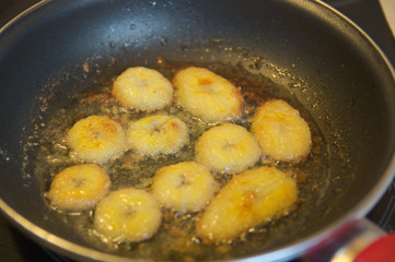 Sliced banana floured in a pan frying