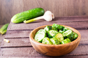 Freshly salted cucumber pickled with garlic and dill in a wooden plate