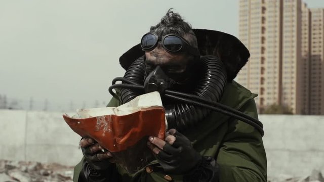 postapocalypse, lonely strong man walks amid garbage dump and abondoned town in special equipment for breath and old specticals. Polution enviroment and soon future. 4K