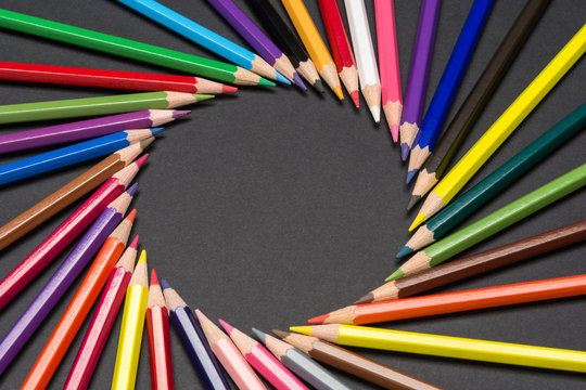 Circular frame made of colored pencil tips, isolated on black cardboard