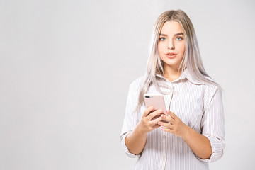 Photo of cheerful cute business beautiful young woman chatting by mobile phone isolated over white wall background.
