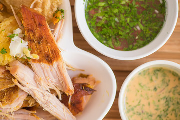Close up of delicous hornado with mashed potatoes with salad, tostado and mote with two smalls...