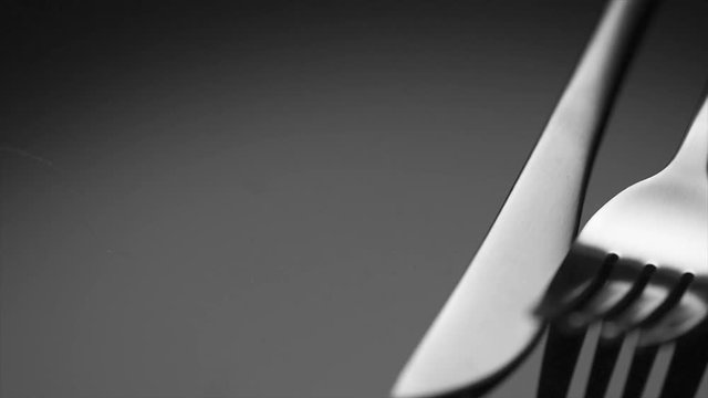 Luxury cutlery closeup. Knife and fork over black background. Rotation 360 degrees. 4K UHD video
