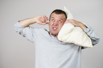 Sleepy man with pillow closing his ear