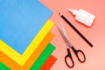 Items for creativity - sheets of colored cardboard, scissors, pencil and glue on a red background....