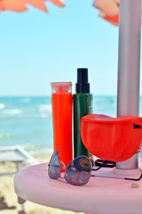 prodotti per la protezione della pelle dai raggi solari appoggiati sotto l'ombrellone in spiaggia