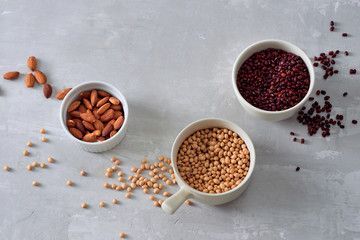 various dried beans with kitchen utensils on gray table, top view
