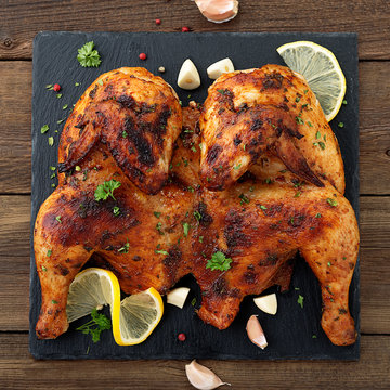 Grilled fried roast Chicken Tabaka on  wooden background. top view