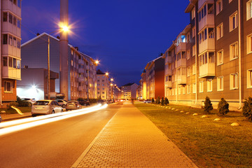 Empty street of town lit by street lights at night.