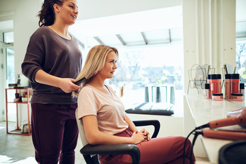 Smiling woman getting her hair done by a salon stylist