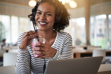 Smiling university student studying and drinking a smoothie betw