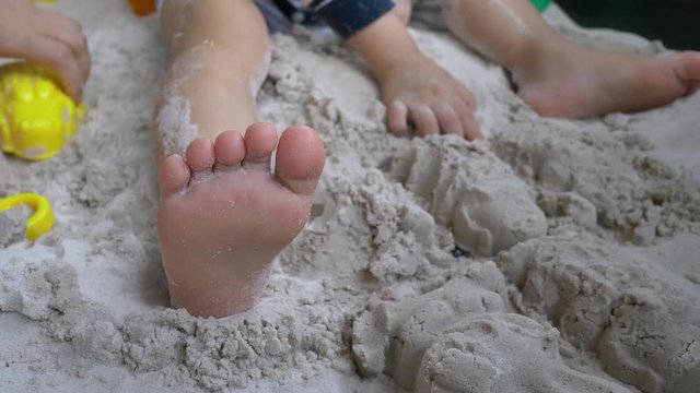 slow motion, closeup foot of child playing sand in playground