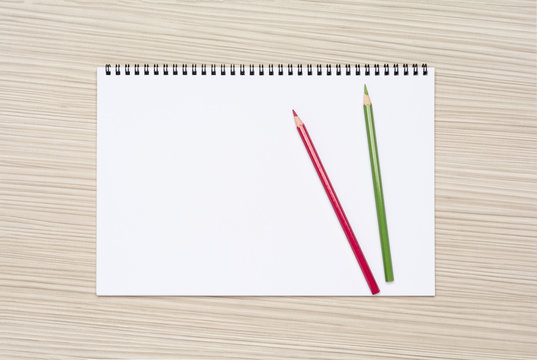 Two colored pencils on a blank page of a sketchbook