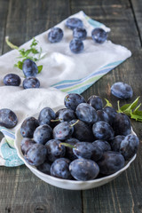 Berries plum in a plate on a wooden table