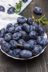 Berries plum in a plate on a wooden table