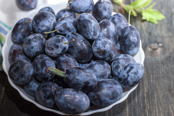 Berries plum in a plate on a wooden table