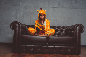 Pajamas for Halloween in the form of a kangaroo. Emotional portrait of a girl on a sofa background....