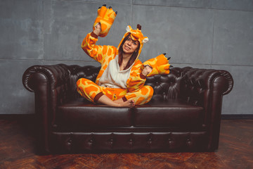 Pajamas for Halloween in the form of a kangaroo. Emotional portrait of a girl on a sofa background....