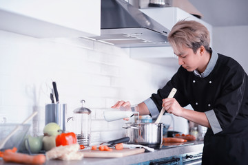 Asian cook in the kitchen prepares food in a cook suit