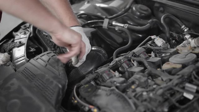 Close-up shot of a professional car mechanic fixing a part under the hood of the car, fixing car engine.