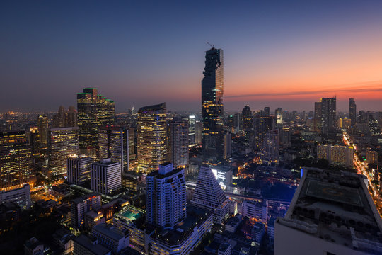 Scenic view of MahaNakhon and many other lit skyscrapers in downtown Bangkok, Thailand, from above in the evening.